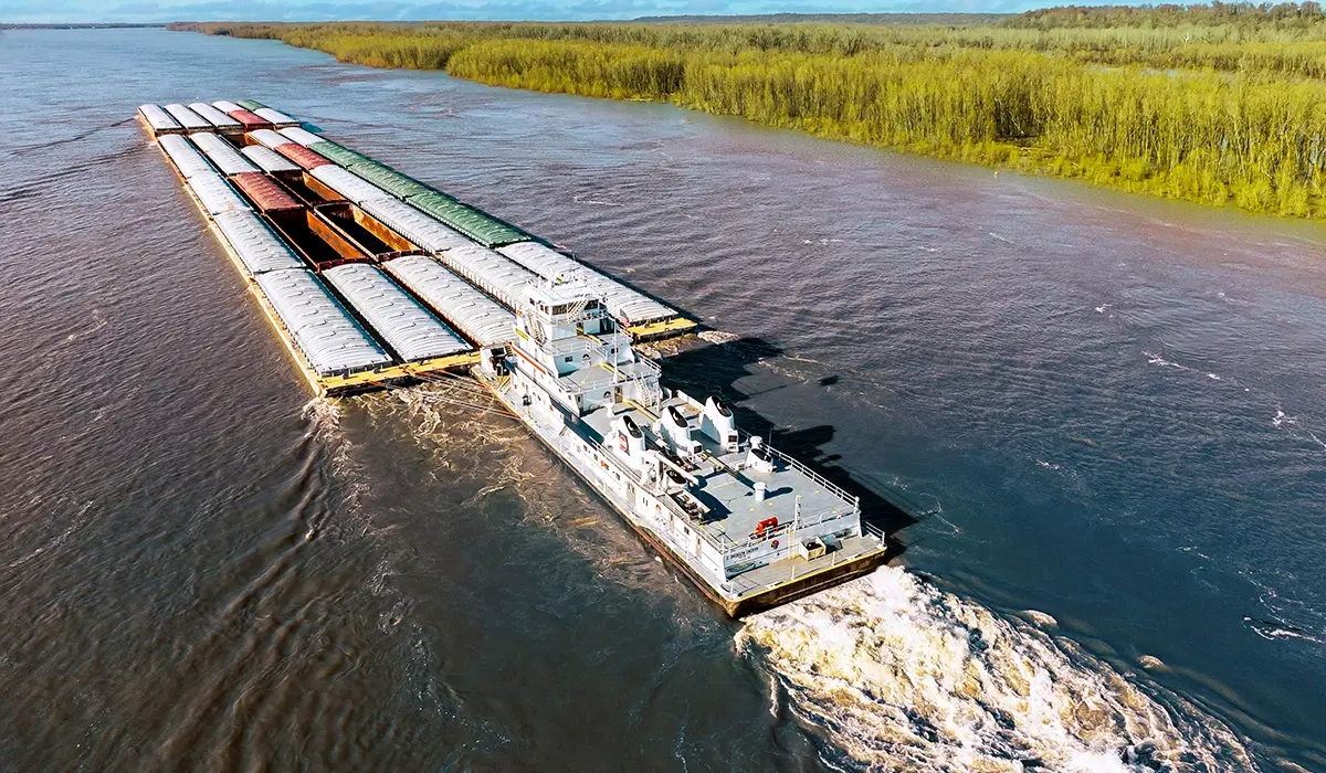 Ingram barge on river with large wake Ingram barge on river with large wake